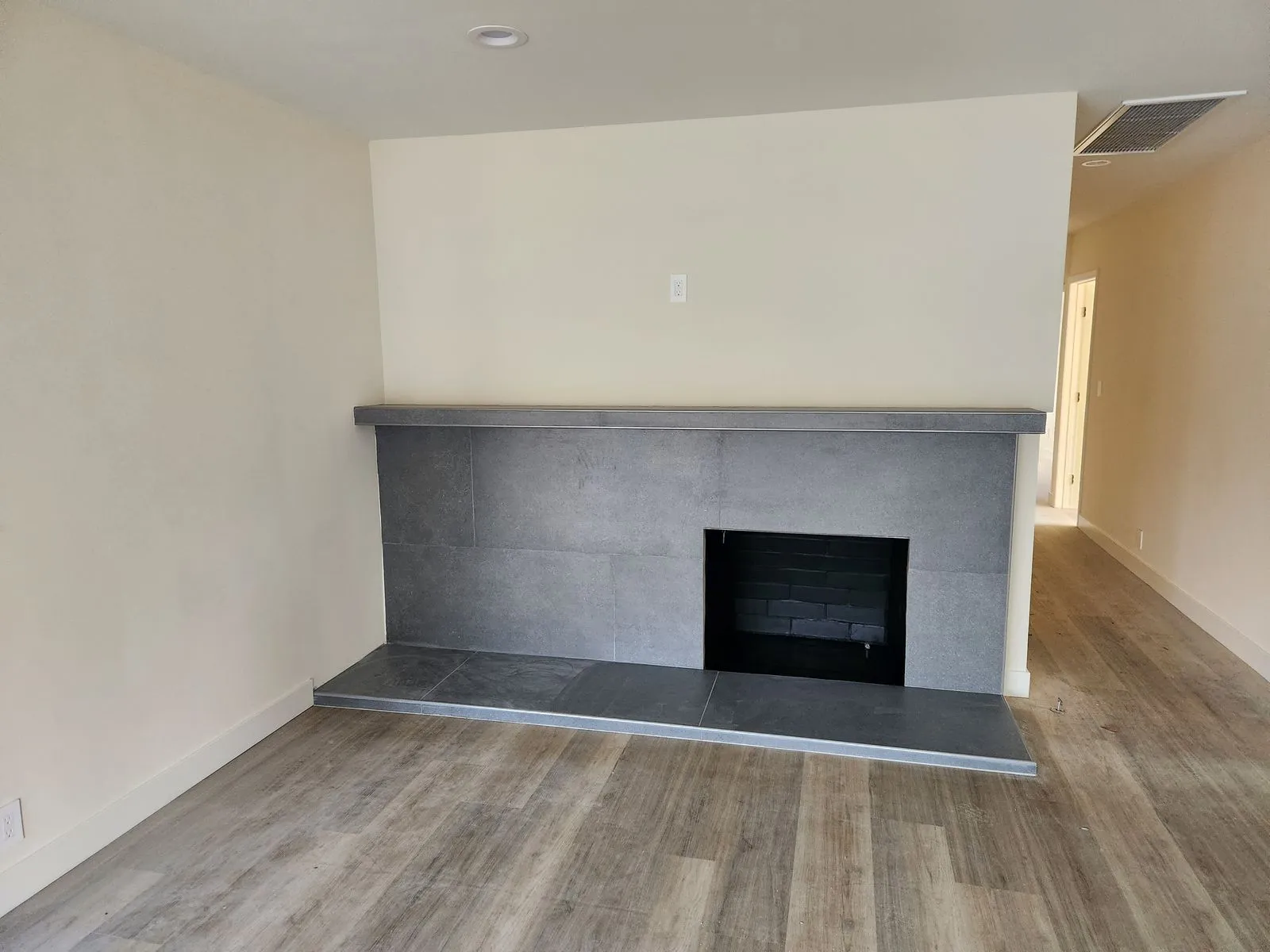Renovated living room with modern gray tile fireplace surround and new flooring