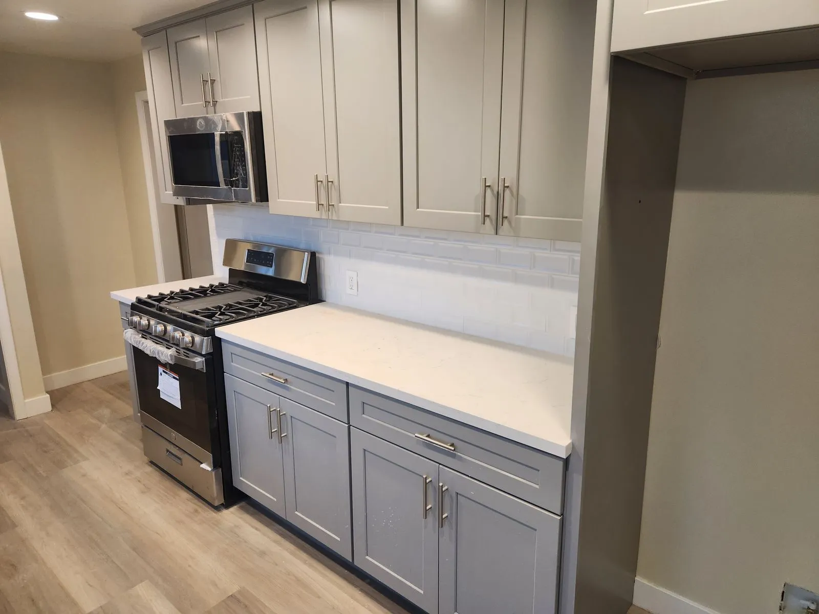 Renovated kitchen with gray shaker cabinets, quartz countertops, and subway tile backsplash