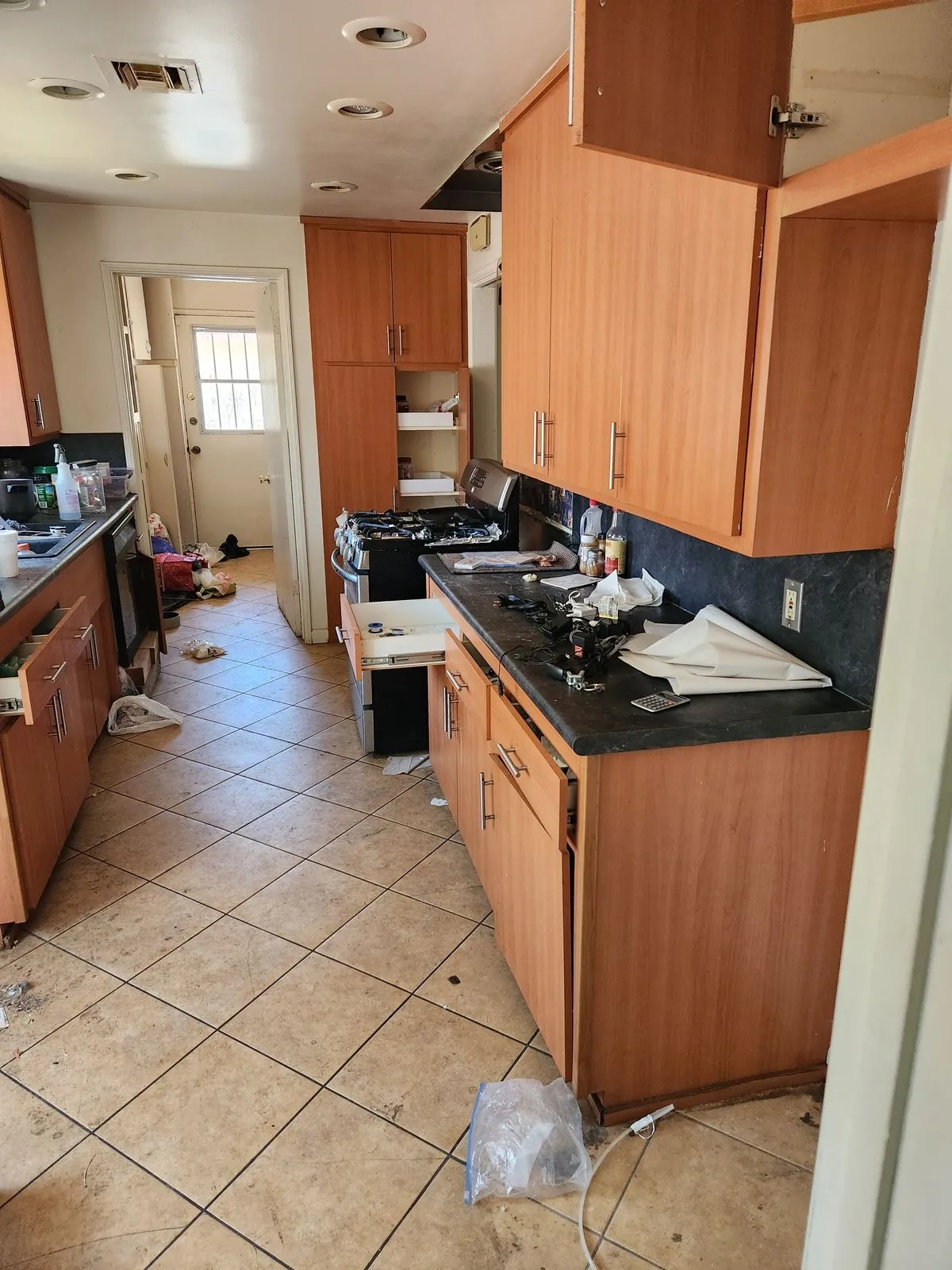 Dated kitchen with old wood cabinets, dark countertops, and tile flooring