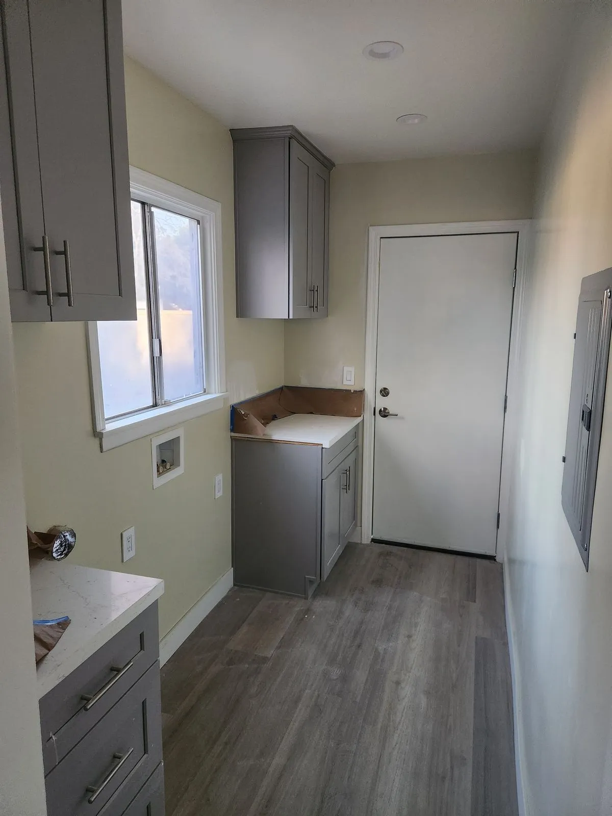 Renovated laundry room with gray cabinets, new flooring, and modern fixtures