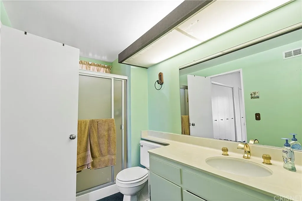 Dated master bathroom with green walls, old shower doors, and brass fixtures