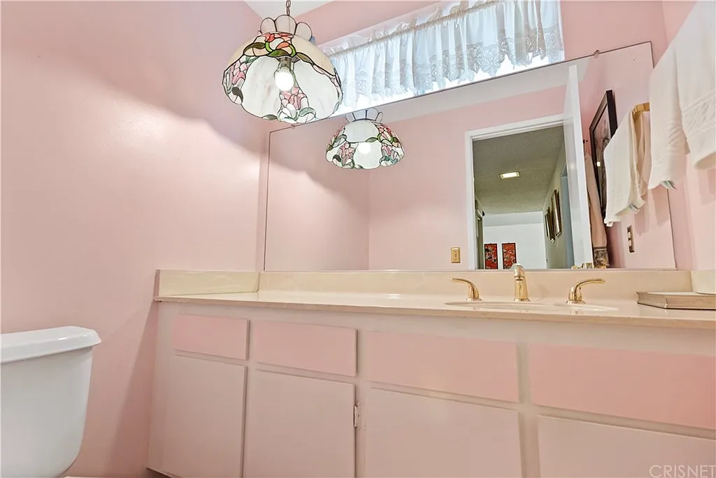 Dated pink bathroom with Tiffany lamp and brass fixtures