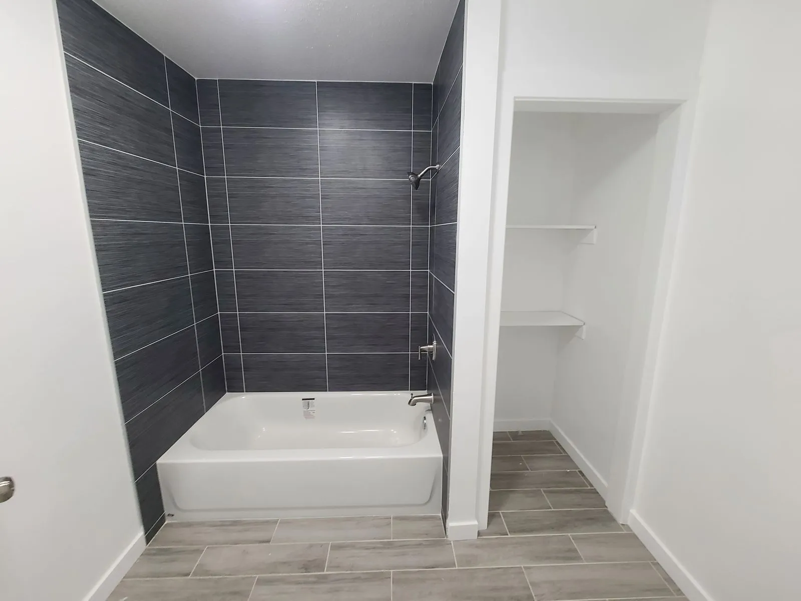 Bathroom with dark gray tile surround and bathtub