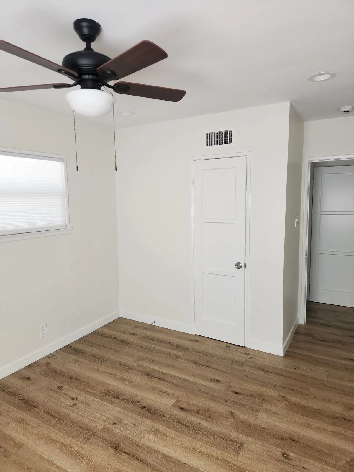 Bedroom with new flooring and ceiling fan installed
