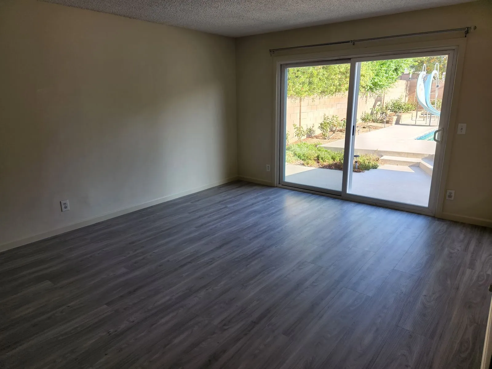 Living room with new flooring and sliding door to pool area